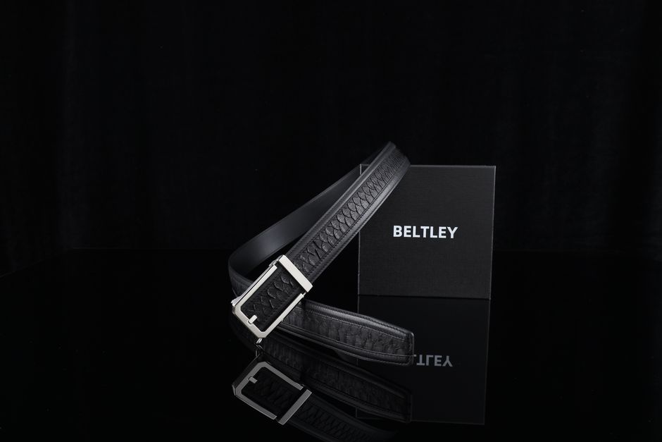 Luxury black leather belt elegantly displayed with a designer box on a reflective surface.