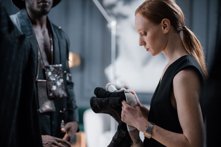 A fashion designer and model prepare for a photoshoot, highlighting modern style.
