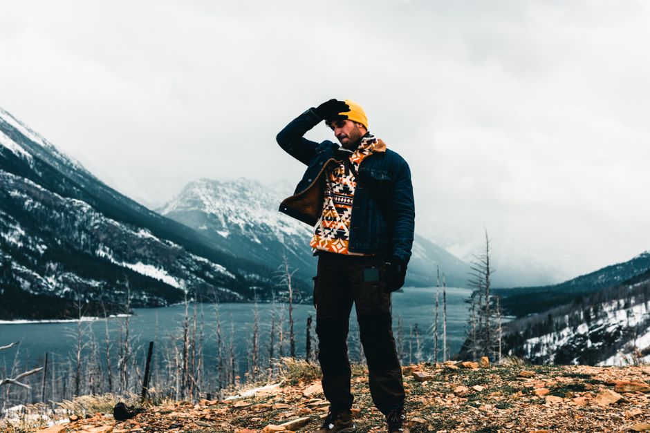 Man in winter attire at Waterton Park, capturing stunning lake and mountain landscape.