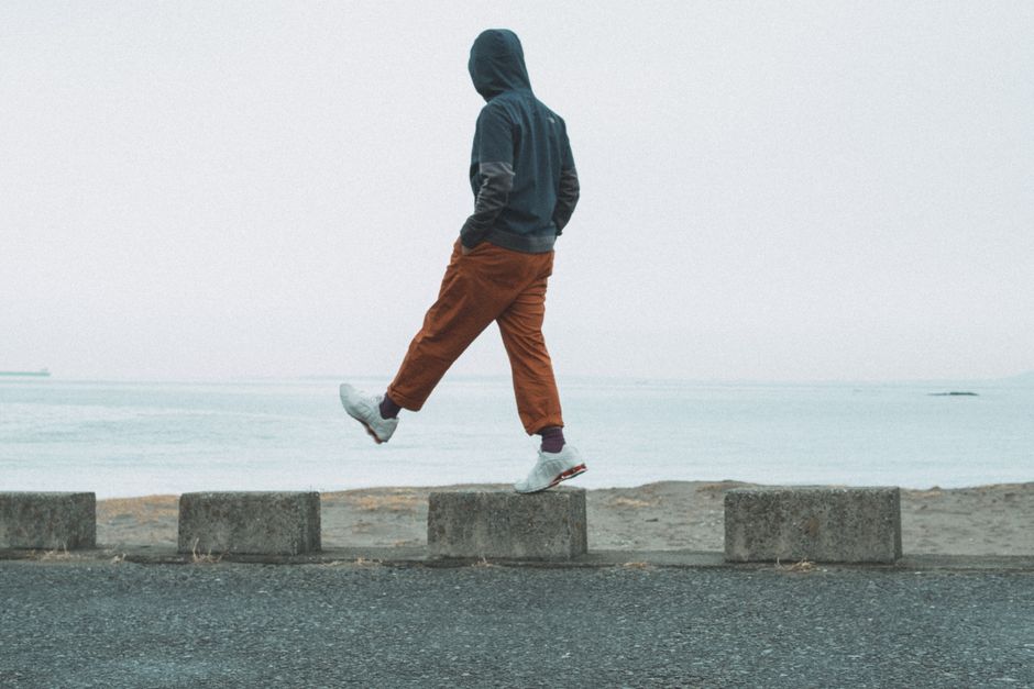 Individual in casual attire balancing on seaside blocks in Chiba, Japan.