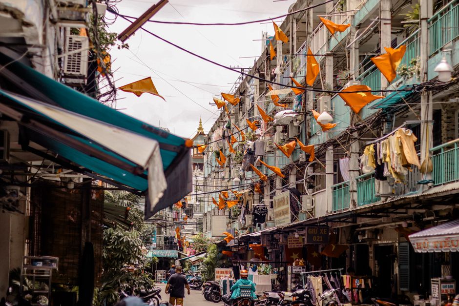 Dynamic city street scene with orange flags and clotheslines, capturing vibrant urban life.