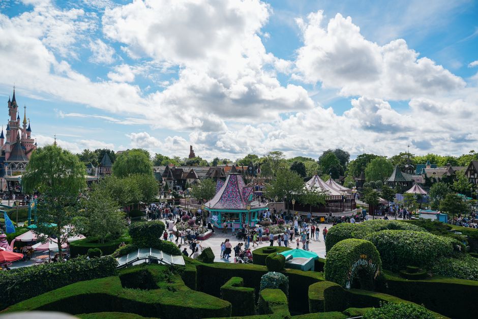 Experience the lively atmosphere of Disneyland Paris with its iconic castle and bustling crowds.