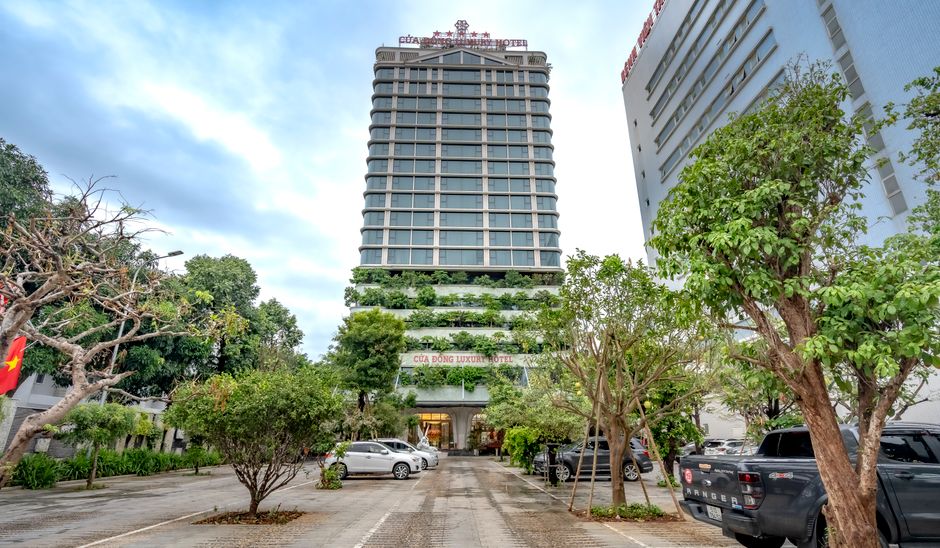 A modern luxury hotel with greenery in a bustling city environment.