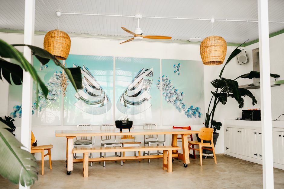 Bright dining space with modern decor, tropical plants, and abstract artwork.