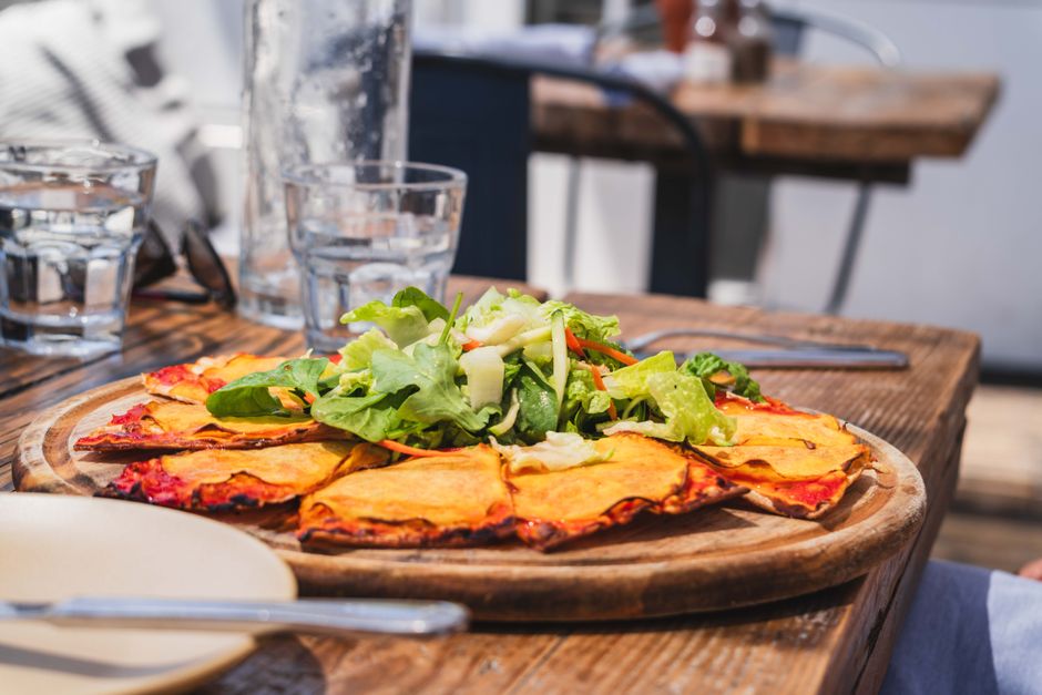 Enjoy a delicious thin crust pizza topped with fresh greens at a Malibu café.