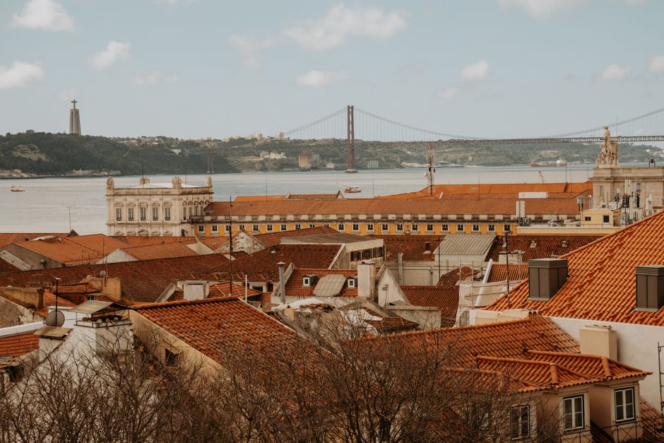 Scenic view of Lisbon's terracotta rooftops with the iconic 25th April Bridge in the background.