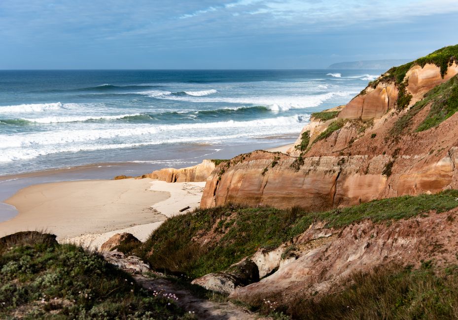 Stunning view of a secluded beach surrounded by cliffs and rolling ocean waves.