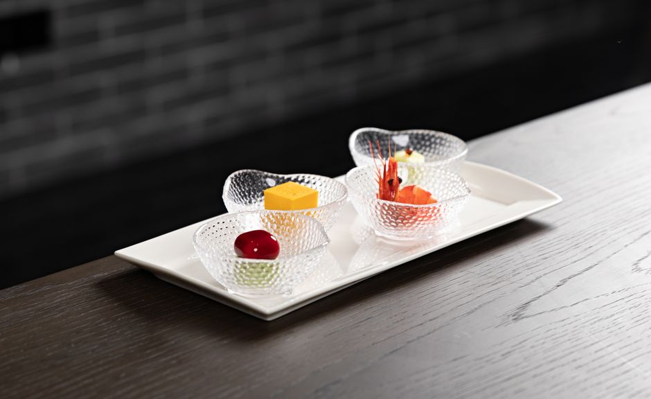 A selection of gourmet appetizers beautifully presented on a white tray in elegant glass bowls.
