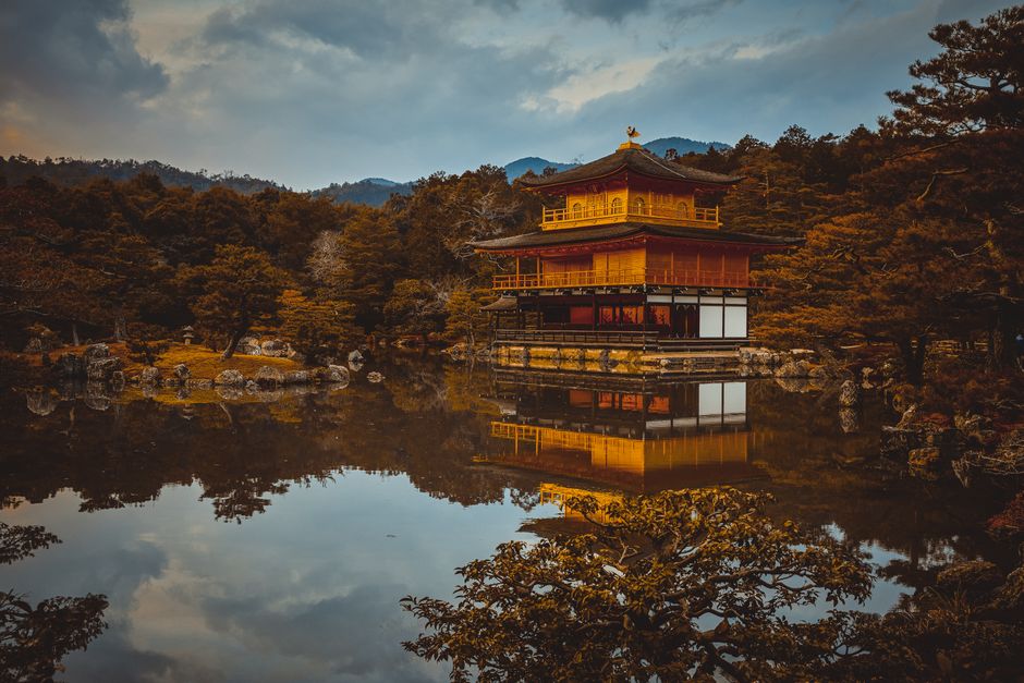Scenic view of the Golden Pavilion in Kyoto reflected in a tranquil pond surrounded by autumn foliage.