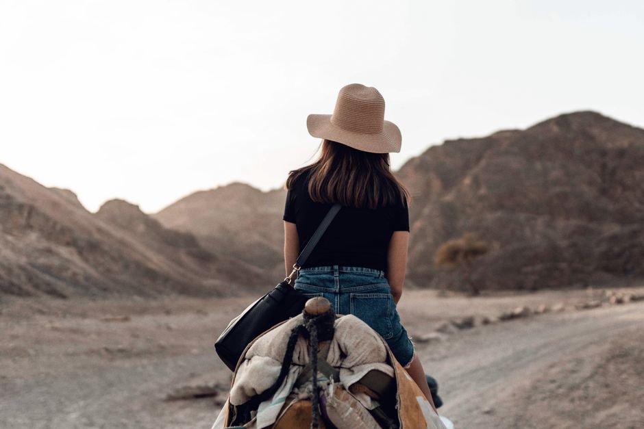 A woman on a camel journeys through a rugged desert landscape, embracing adventure and exploration.