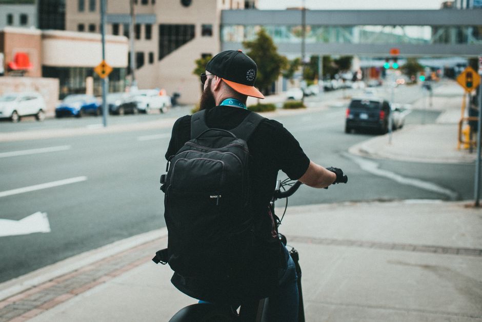 A cyclist with a backpack rides through a city street, showcasing urban commuting lifestyle.