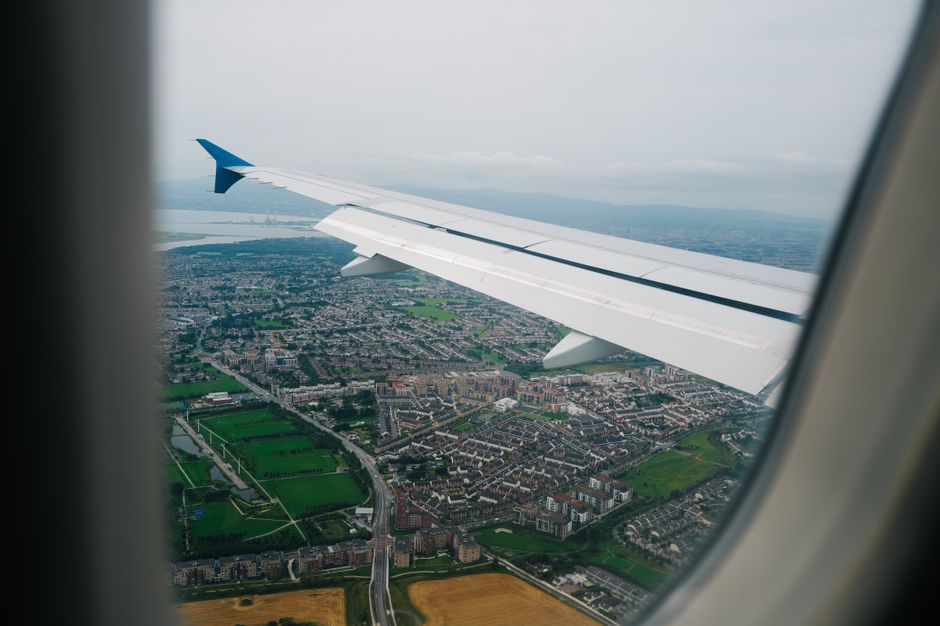 View from an airplane window showing a vibrant cityscape and landscape below, highlighting the journey.