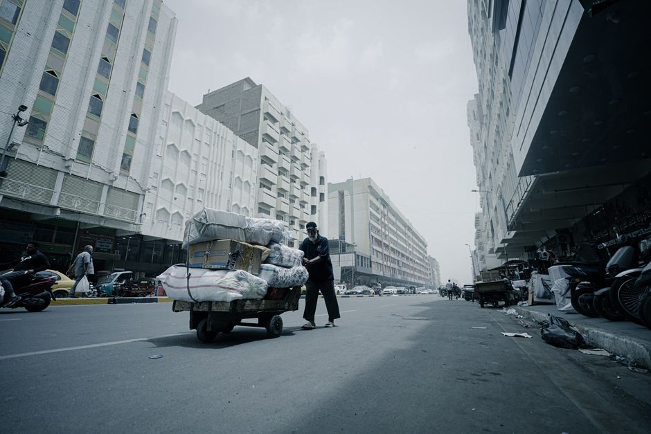 Street vendor pushing a loaded cart in a busy urban street capturing the essence of city life.