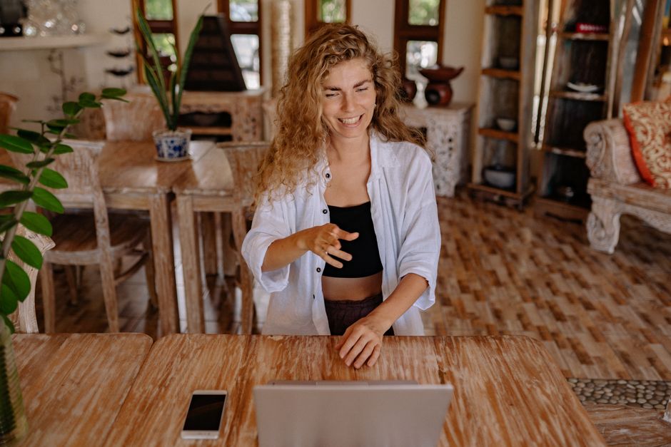 Happy woman working remotely with laptop in a cozy home environment.